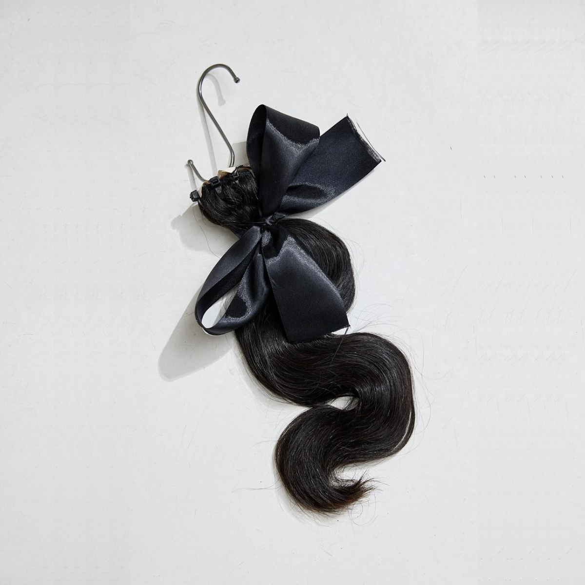 Black hair extensions with a black bow on a white background