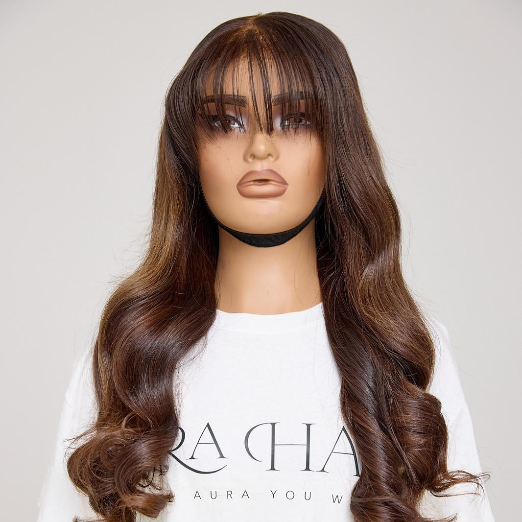 Mannequin head with long brown wig and bangs on a plain background
