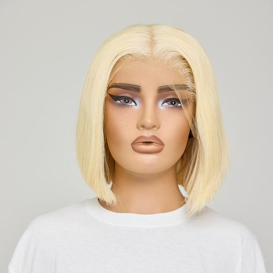 Blonde wig on a mannequin head against a plain background